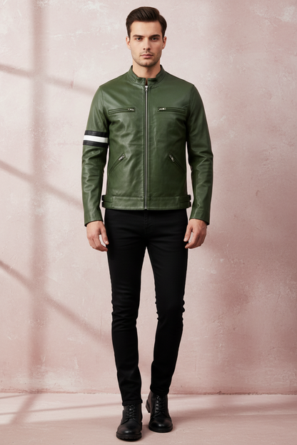 a man wearing an olive green cafe race biker leather jacket , dirk gently with a black pants, standing against a light maroon textured wall
