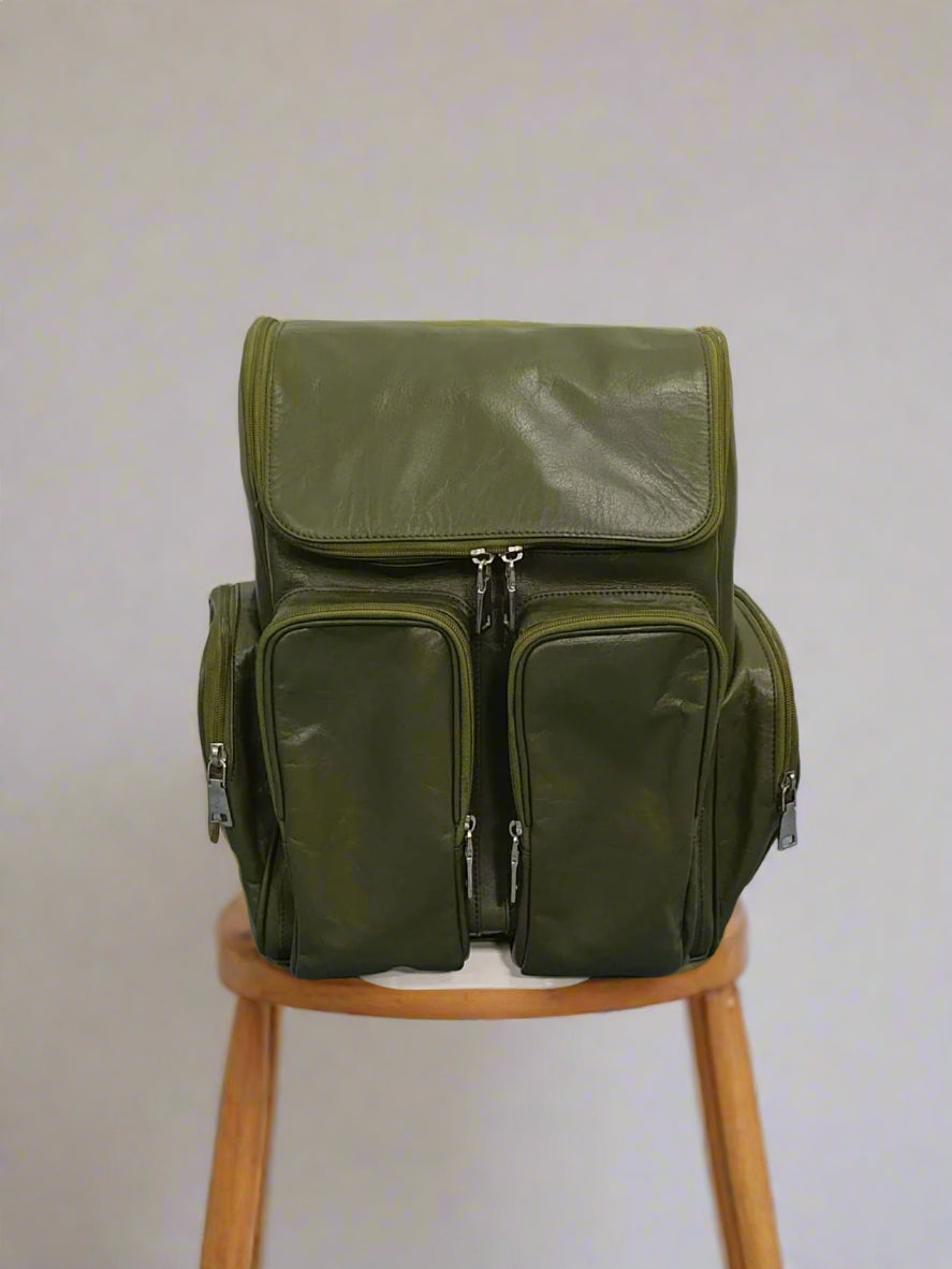 Green backpack on a gray floor with a white wall background