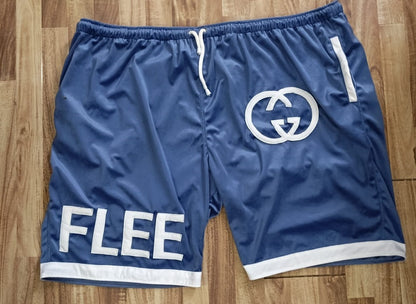Blue velvet shorts with GG logo and 'FLEE' text on a wooden floor