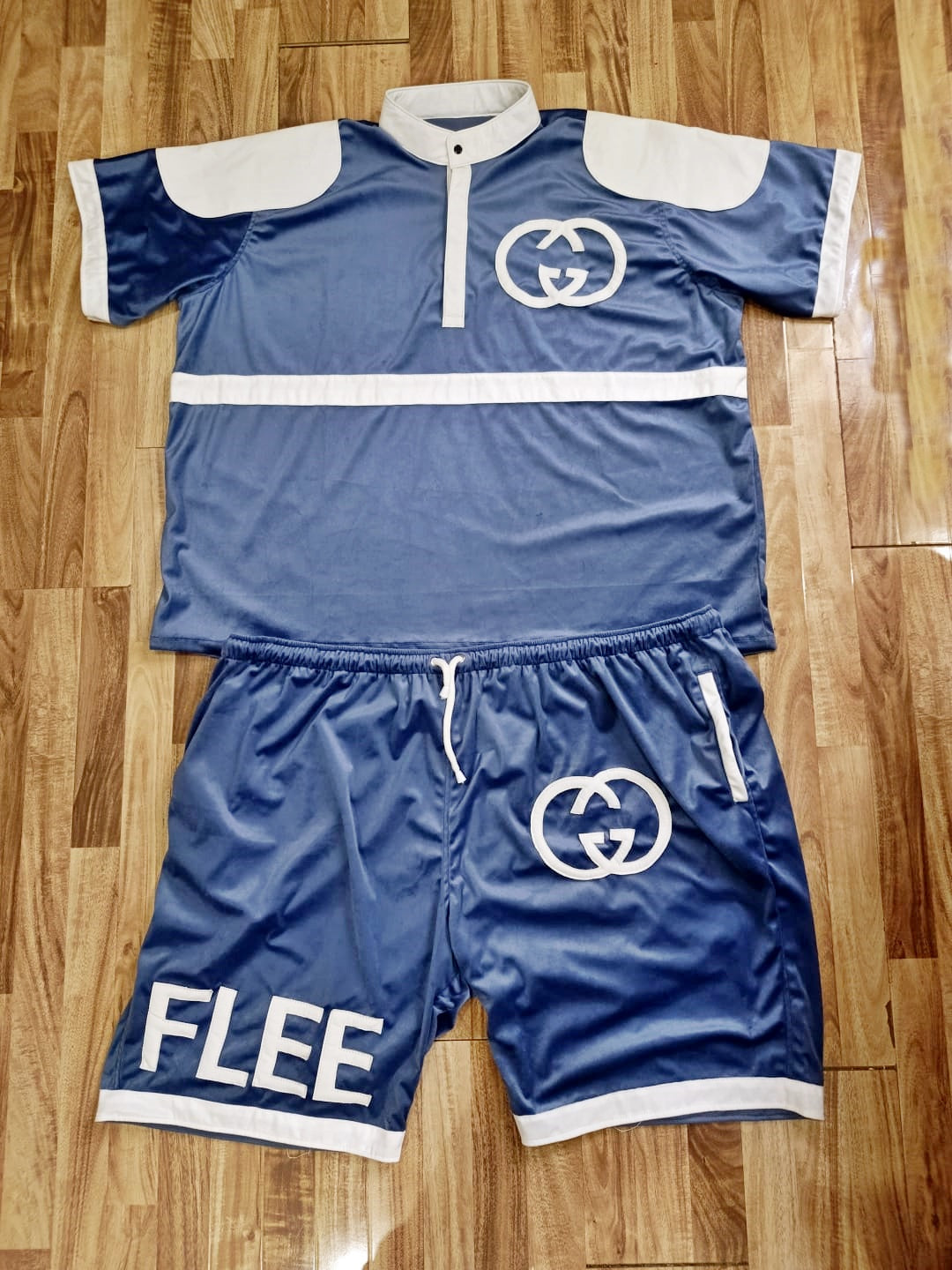 Blue velvet half sleeves shirt and shorts with GG logo and white accents on a wooden floor