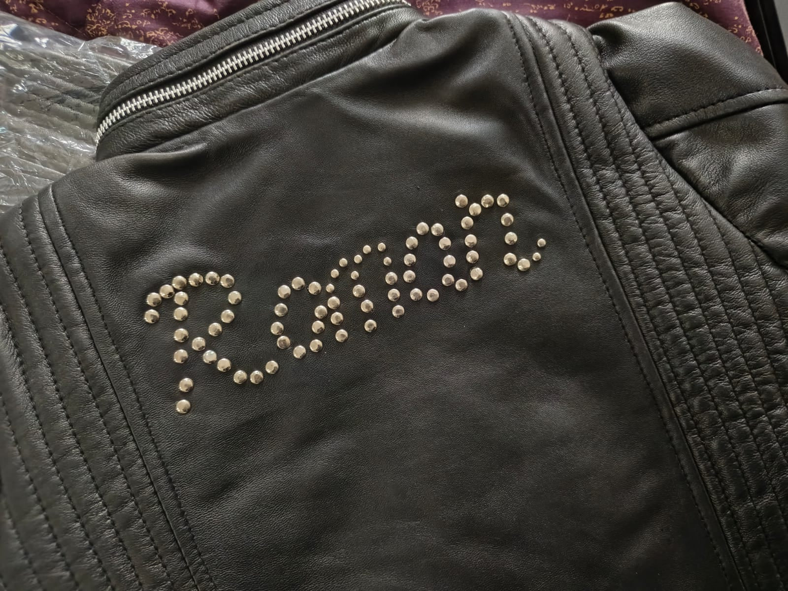 Black leather jacket with custom name studded design on a textured surface