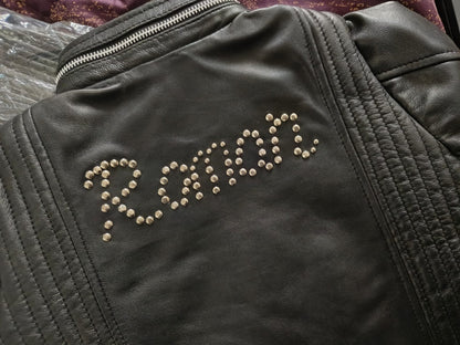 Black leather jacket with custom name studded design on a textured surface