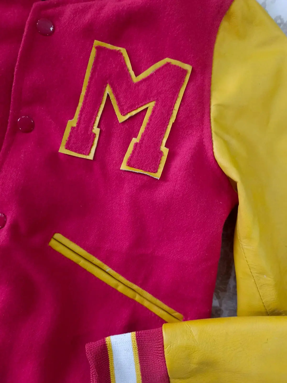 Close-up of a red and yellow letterman jacket with a large 'M' emblem.