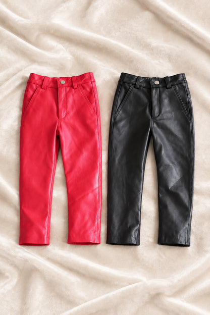 kids black leather pants and red leather pants laid over a velour fabric front view