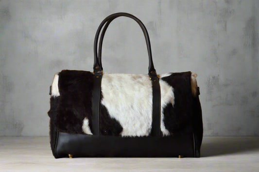 Black and white fur-patterned handbag on a wooden surface with a textured beige wall background